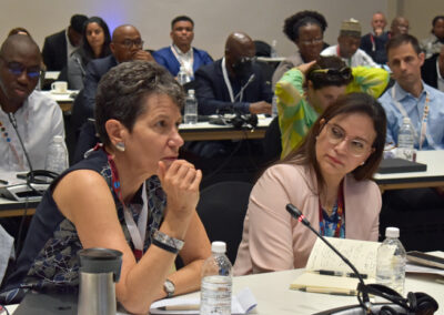 Two women sit next to each other in a classroom, one is speaking into a microphone.