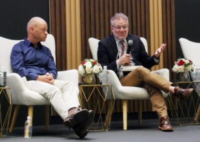 Two men sit next to each other on a stage.