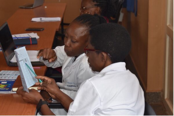 Two African women look at a flyer together. 