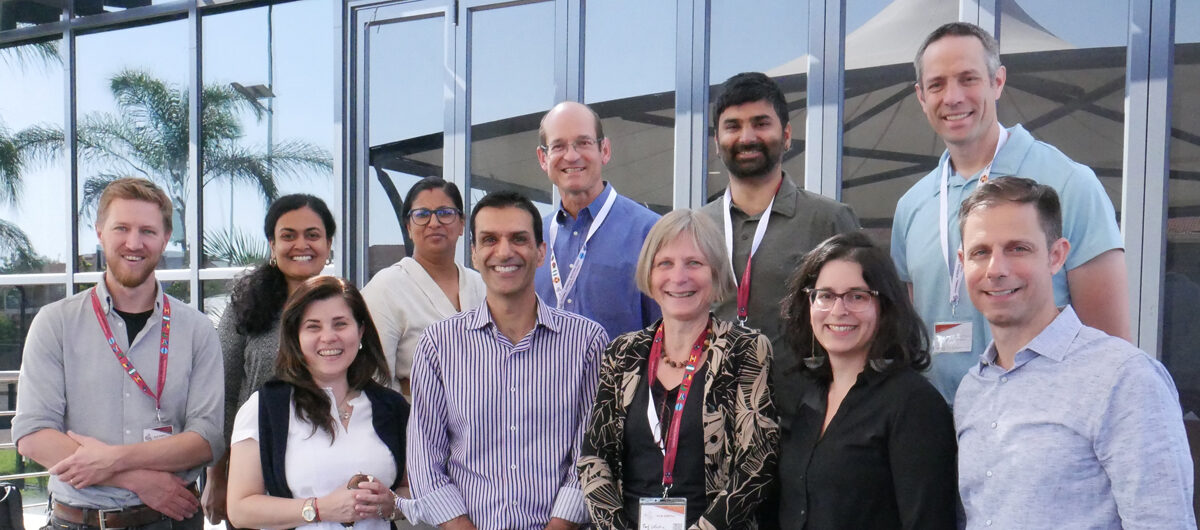 A group of 10 people pose for a photo, smiling at the camera.